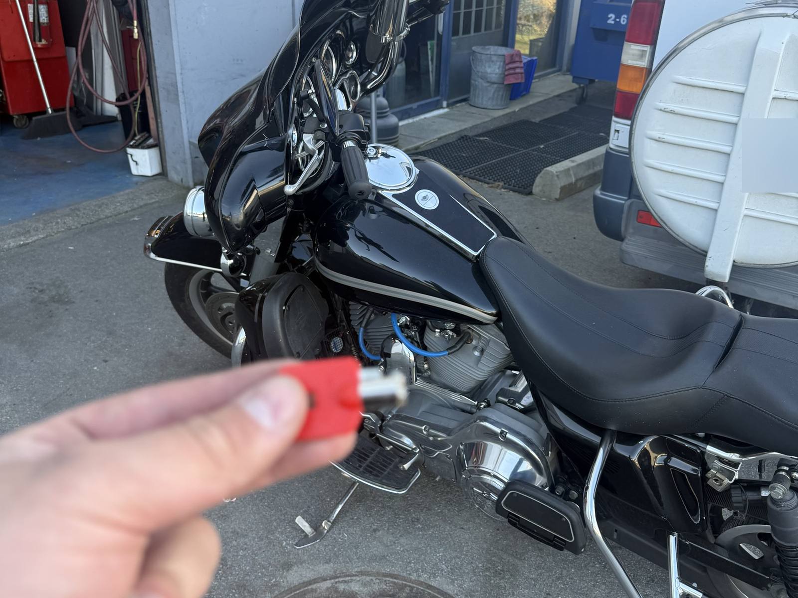 Black Harley-Davidson touring motorcycle with a hand holding a red-headed key