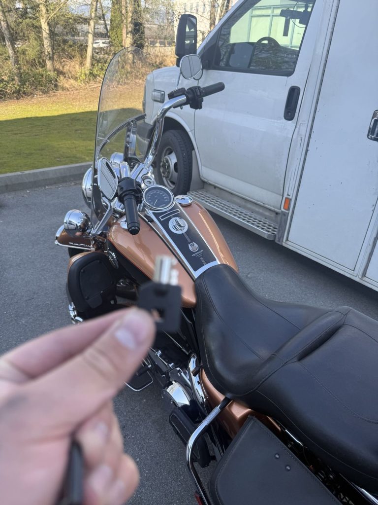 Hand holding a motorcycle ignition key beside a Harley-Davidson touring motorcycle in Vancouver
