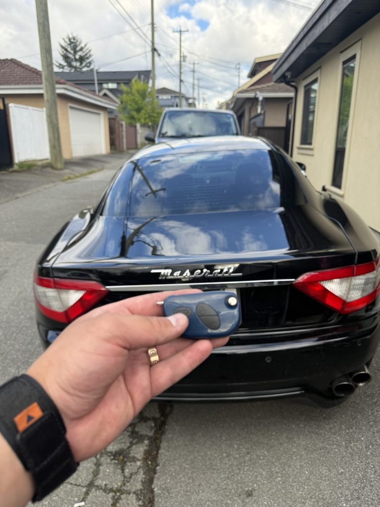 Hand holding a Maserati key behind a black Maserati GranTurismo in a Vancouver laneway