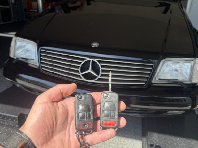 Classic black Mercedes-Benz SL in a Vancouver garage with a hand holding two Mercedes key fobs