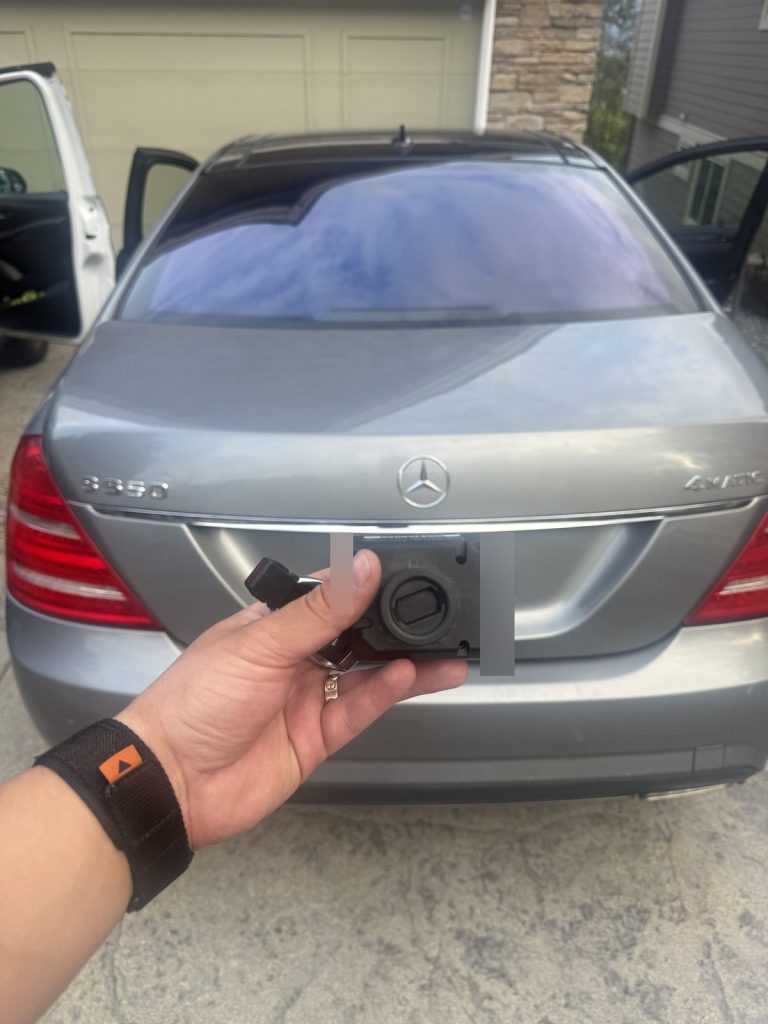 Hand holding a Mercedes-Benz key and a control module behind a grey Mercedes-Benz S-Class in a Vancouver driveway