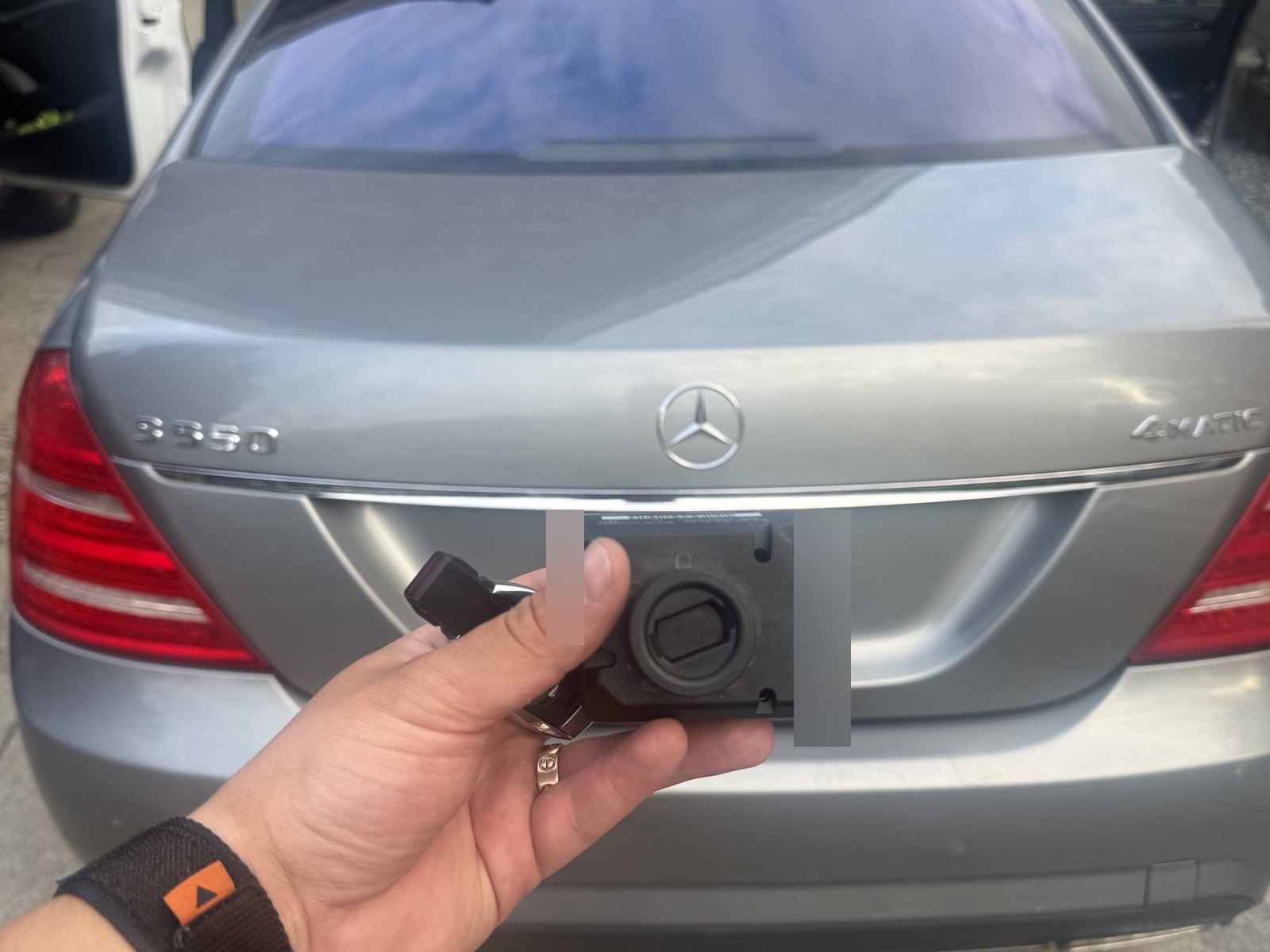 Hand holding a Mercedes-Benz key and a control module behind a grey Mercedes-Benz S-Class