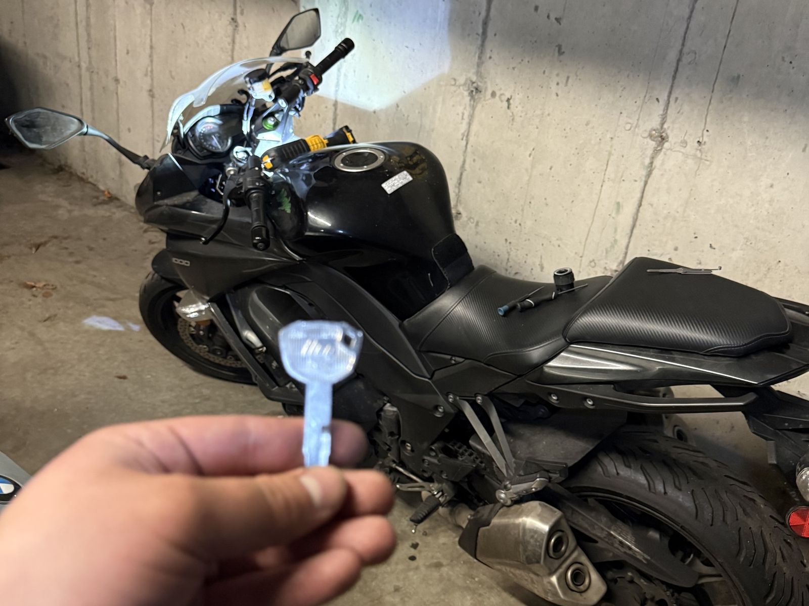 Black sport-touring motorcycle in a Vancouver parkade with a hand holding a motorcycle key