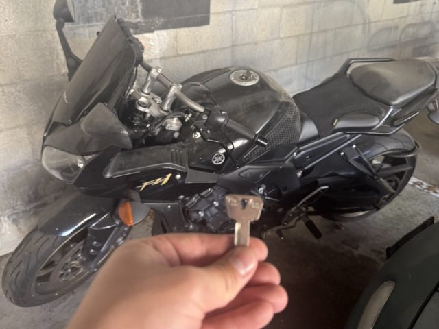 Black Yamaha motorcycle in a Vancouver parkade with a hand holding a cut key