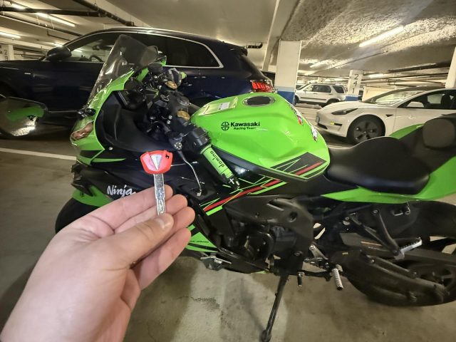 Green Kawasaki Ninja in a Vancouver parkade with a hand holding a red motorcycle key