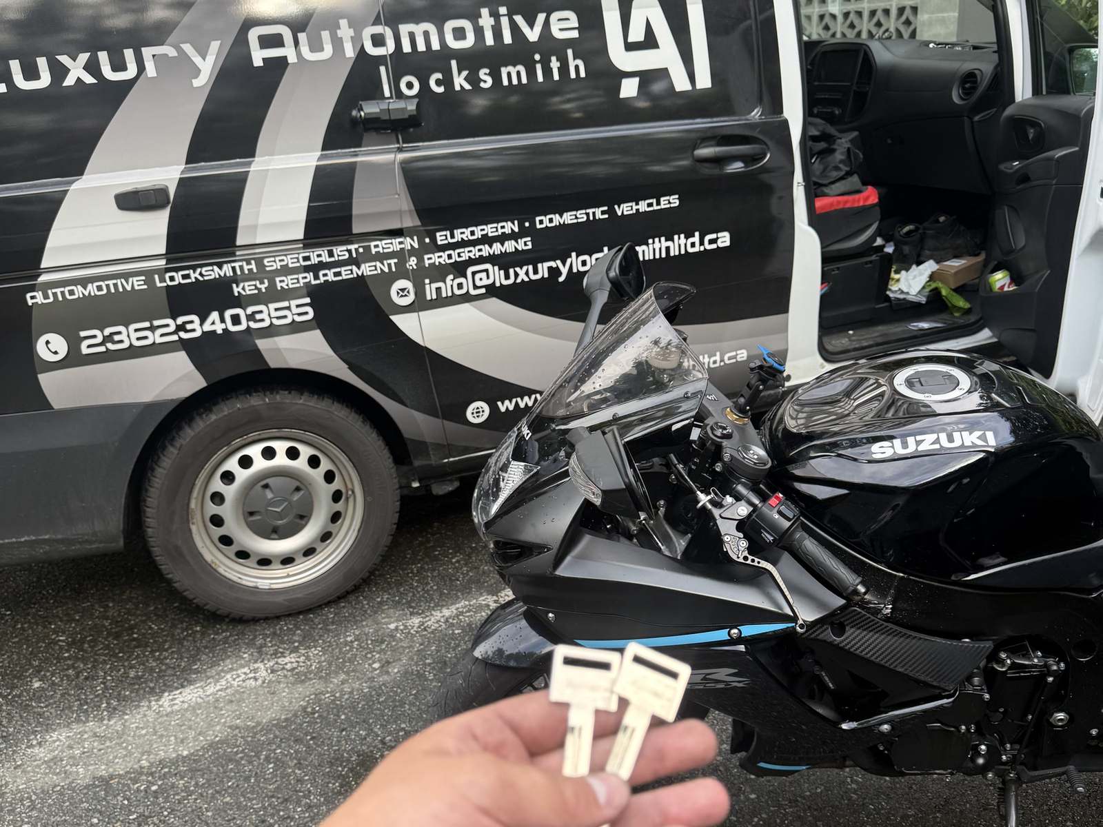 Black Suzuki motorcycle and two motorcycle keys beside the Luxury Automotive Locksmith van