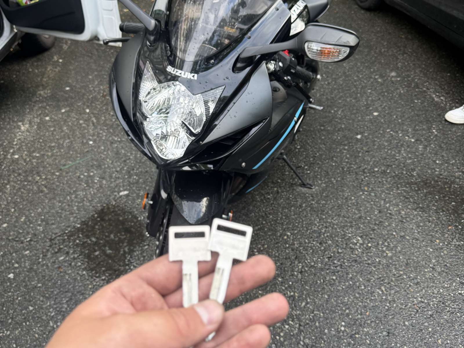 Black Suzuki sport motorcycle with a hand holding two motorcycle keys