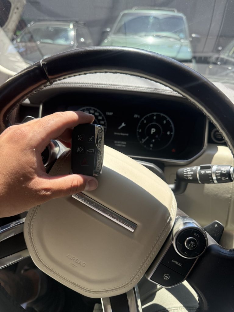 Hand holding a Range Rover key fob over the steering wheel of a Range Rover in Vancouver